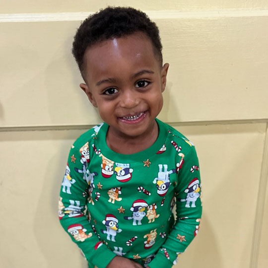 Small child in Christmas pajamas.